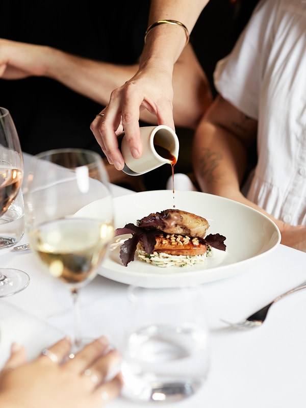a hand pouring sauce on a Locale dish in Noosa