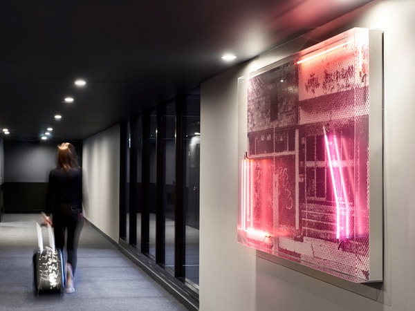 a woman pulling her luggage along Canberra's Midnight Hotel corridor