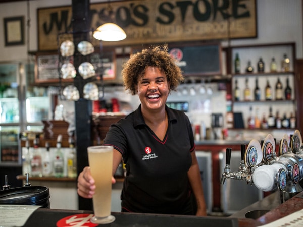 a bartender smiling while holding a drink at Matso’s Brewery & Restaurant, Broome