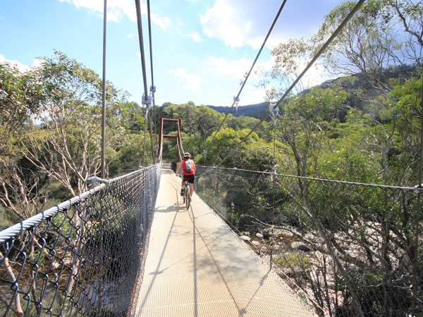 a mountain biker crossing a suspension bridge at Thredbo Valley Track