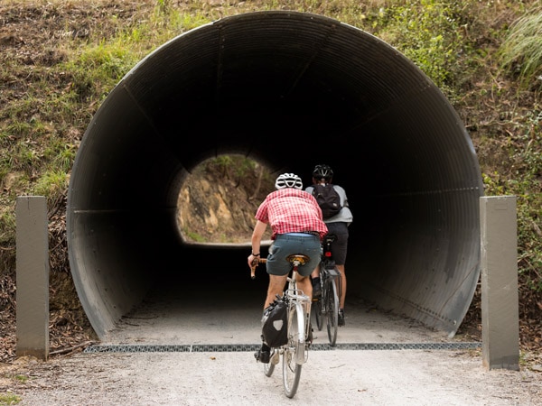 Two people riding bikes in a tunnel.