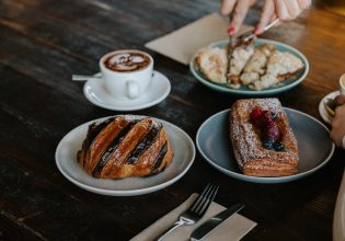 a hand slicing decadent pastries on the table at Wildflour Bakery in Canberra