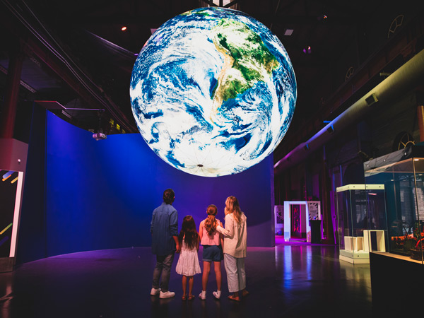 a family admiring the planet Earth replica at Newcastle Museum