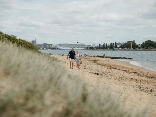 a couple walking along Nobbys Beach