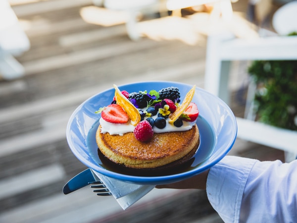 a hand holding a plate of pancakes at The Boathouse, Palm Beach