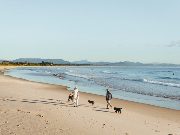 two people walking with dogs on Belongil Beach