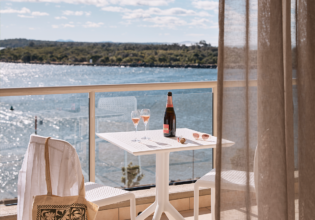 Wine on the balcony at the deluxe king room of Rydges Port Macquarie with water views.