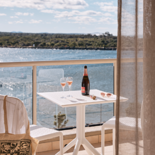 Wine on the balcony at the deluxe king room of Rydges Port Macquarie with water views.