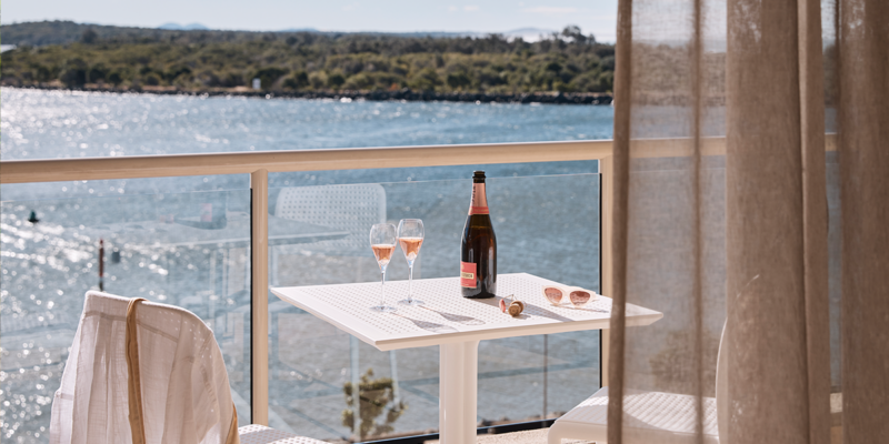 Wine on the balcony at the deluxe king room of Rydges Port Macquarie with water views.