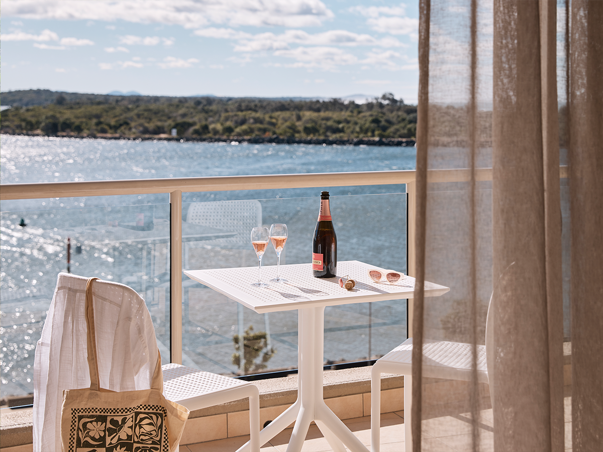 Wine on the balcony at the deluxe king room of Rydges Port Macquarie with water views.