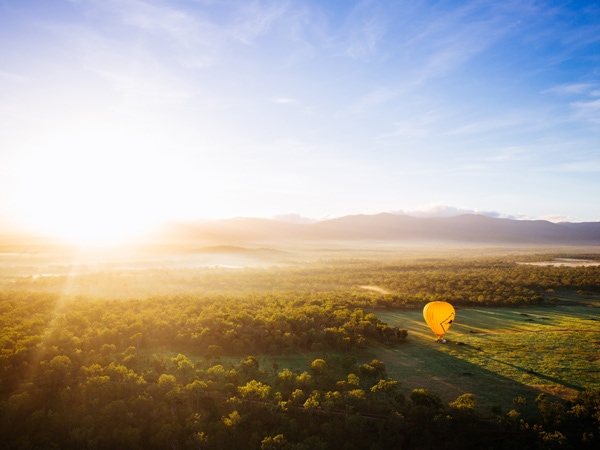 an aerial view of a hot air balloon crossing scenic landscapes in Cairns
