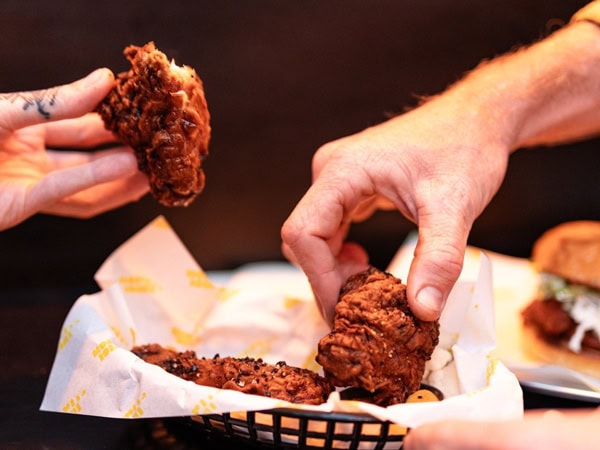 hands holding chicken wings at Morty's Joint, Sawtell