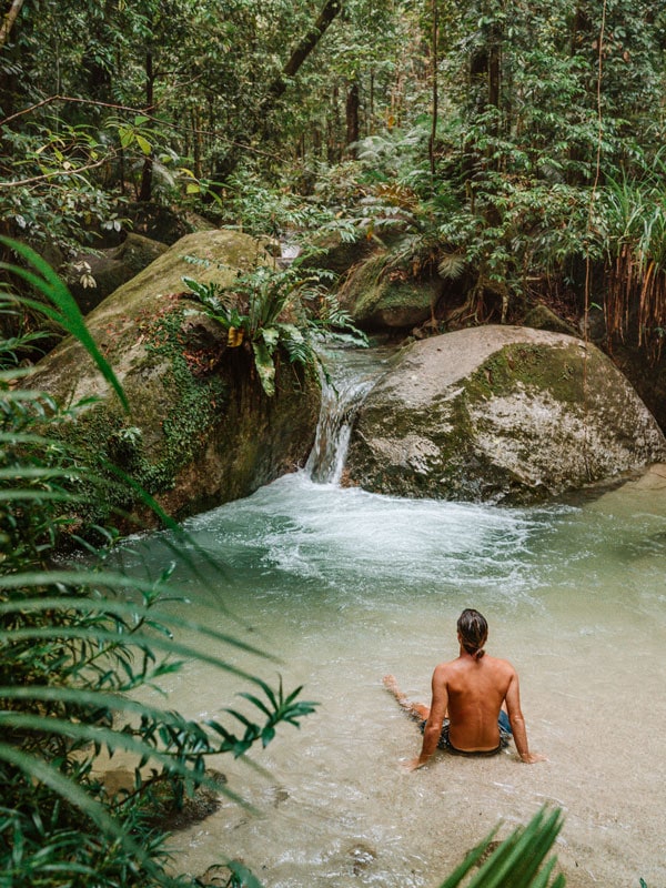 a man sitting in the water at Mossman Gorge in the Daintree Rainforest