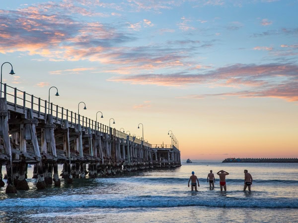 surfers at the pier of Jetty Beach. during sunrise