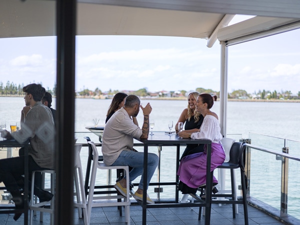 people enjoying lunch on the waterfront balcony at Queen’s Wharf Hotel