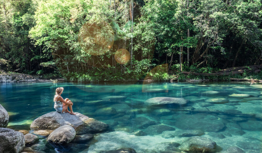a woman sitting on a rock at Mossman Gorge, Port Douglas