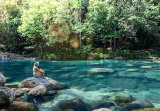 a woman sitting on a rock at Mossman Gorge, Port Douglas