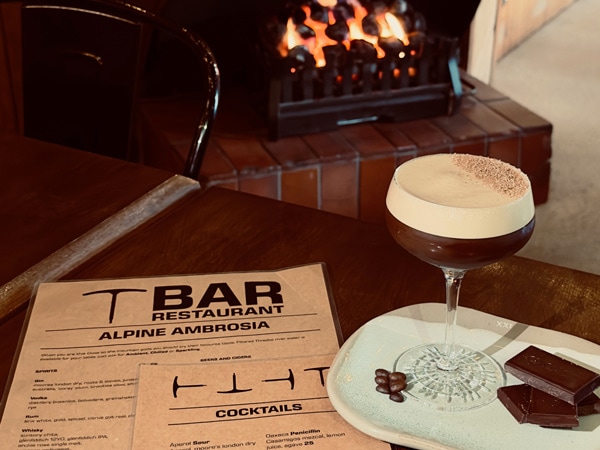 a glass of cocktail alongside T Bar Restaurant menu