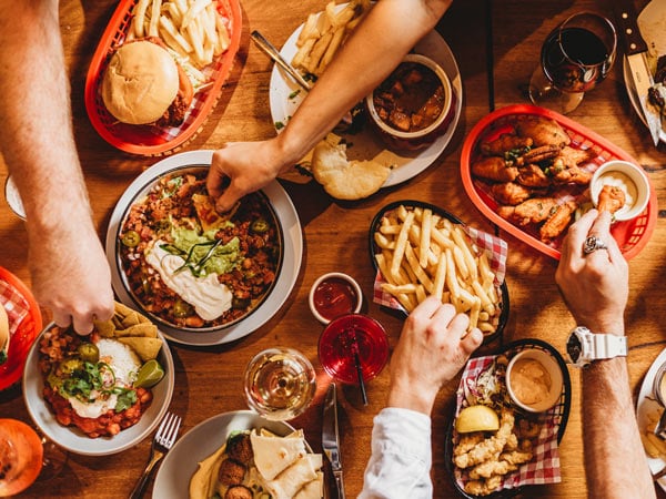 a table-top view of hands reaching for food at The Local Pub