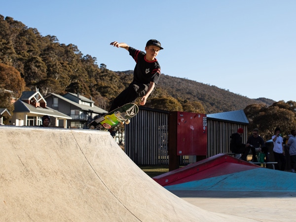 a boy practicing how to skateboard on a mini ramp at Thredbo Skate Park