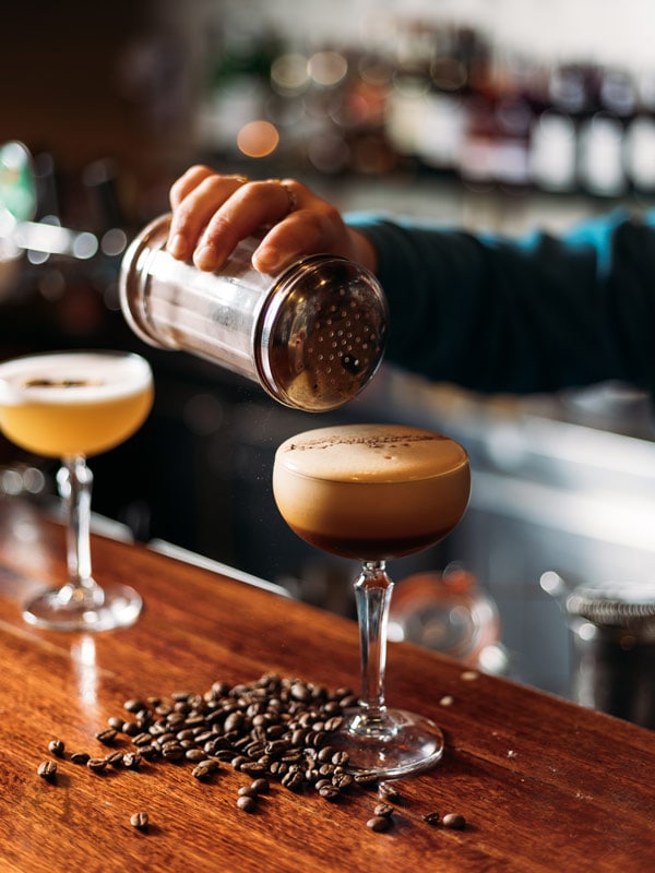 a hand pouring spices on a cocktail drink at Lounge Bar, Thredbo
