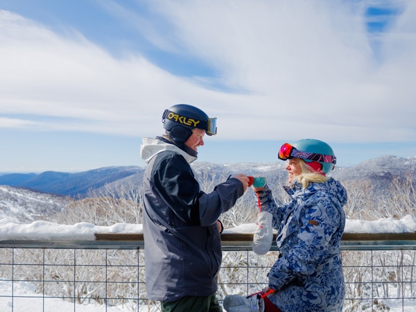 a couple drinking coffee on the balcony of a Thredbo resort