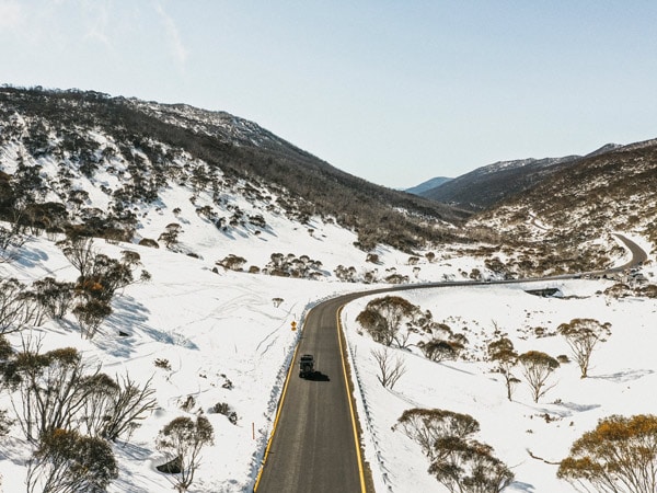 an aerial shot of a car driving along Alpine Way, Thredbo
