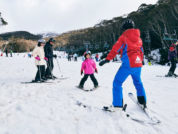 a young girl learning how to ski with an instructor at Thredbo in the Snowy Mountains
