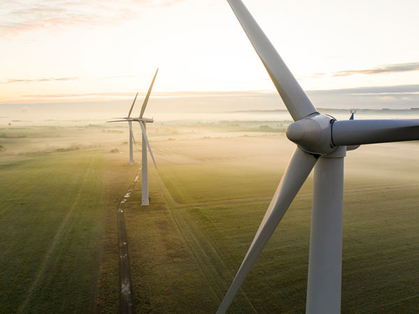 Aerial view of three wind turbines in the early morning fog at sunrise in the English countryside