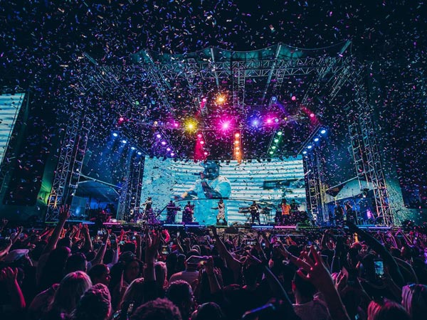 A photo of a festival with a stage and people dancing.