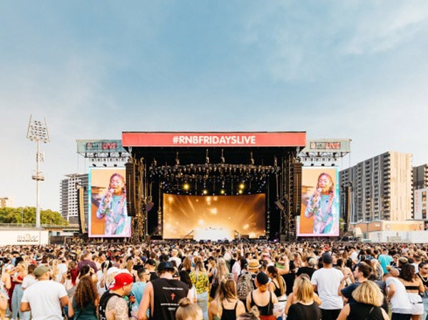 A festival stage with people singing and dancing.