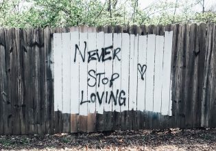 Never stop loving sign painted on fence