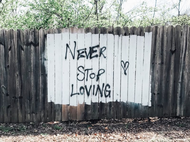 Never stop loving sign painted on fence
