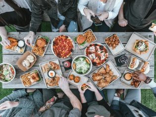 Overhead shot of table with-food-and group of people eating a diverse range of meals
