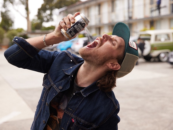 A man drinking beer in the street.