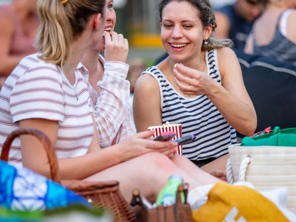 Three women talking and eating popcorn.