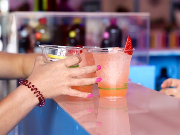 A woman grabbing three cocktail glasses.
