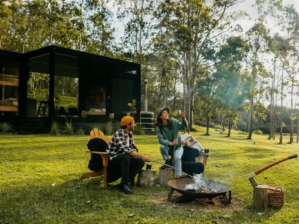 a couple sitting by a small fire setup outside Billy’s Hideaway, hunter Valley