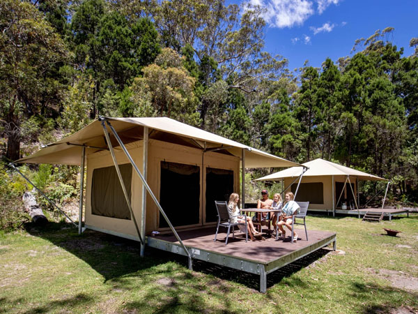 a group sitting outside their tent at Minnie Water Holiday Park