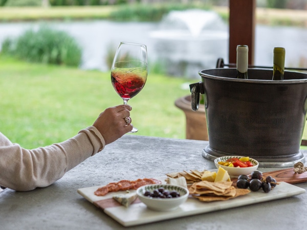 a person holding a glass of wine with charcuterie board on the table at Talits Cellar Door