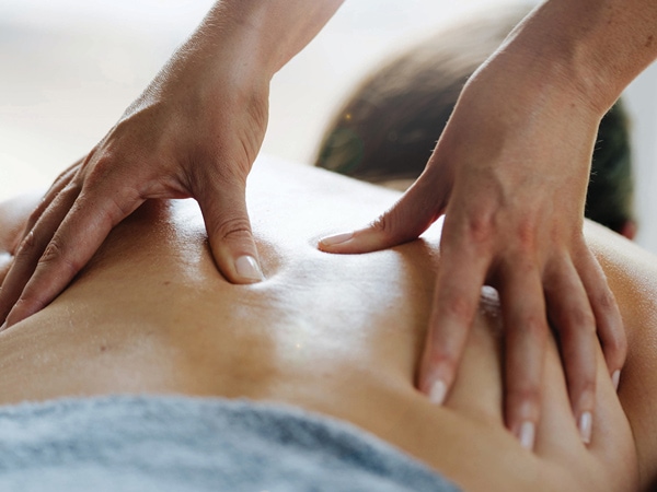 a close-up shot of a massage therapist gently rubbing the back of a client at The Noosa Spa