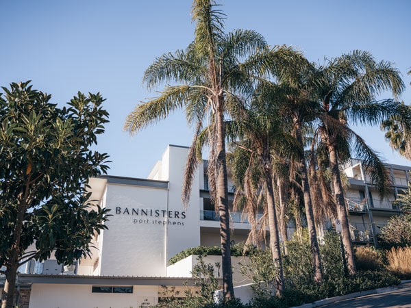 The front of Bannisters Port Stephens with palm trees and blue sky.