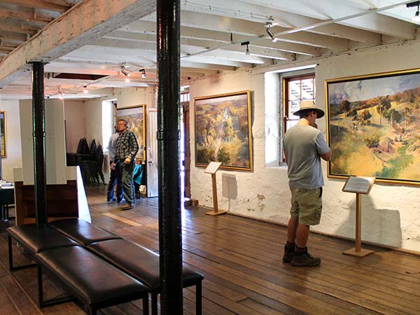 Man viewing paintings on display at the McCrossin's Mill Museum in Uralla.