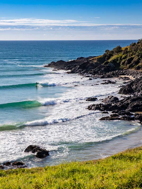 A surfer in the waves at Racecourse Head, Crescent Head. (Image: Destination NSW)