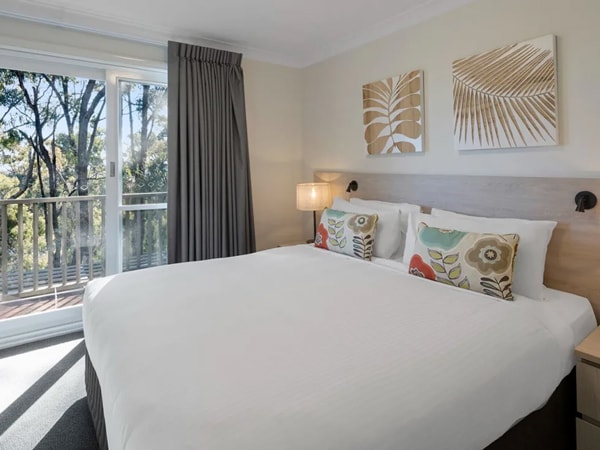 a cosy bedroom with balcony at Oaks Cypress Lakes Resort