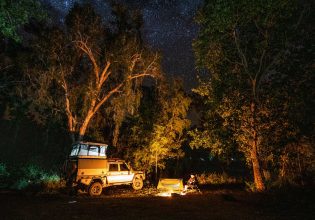 A 4WD is parked by a campfire under the stars at Lorella Springs Wildnerness on the Savannah Way, Northern Territory. (Image: Tourism NT/Sean Scott)