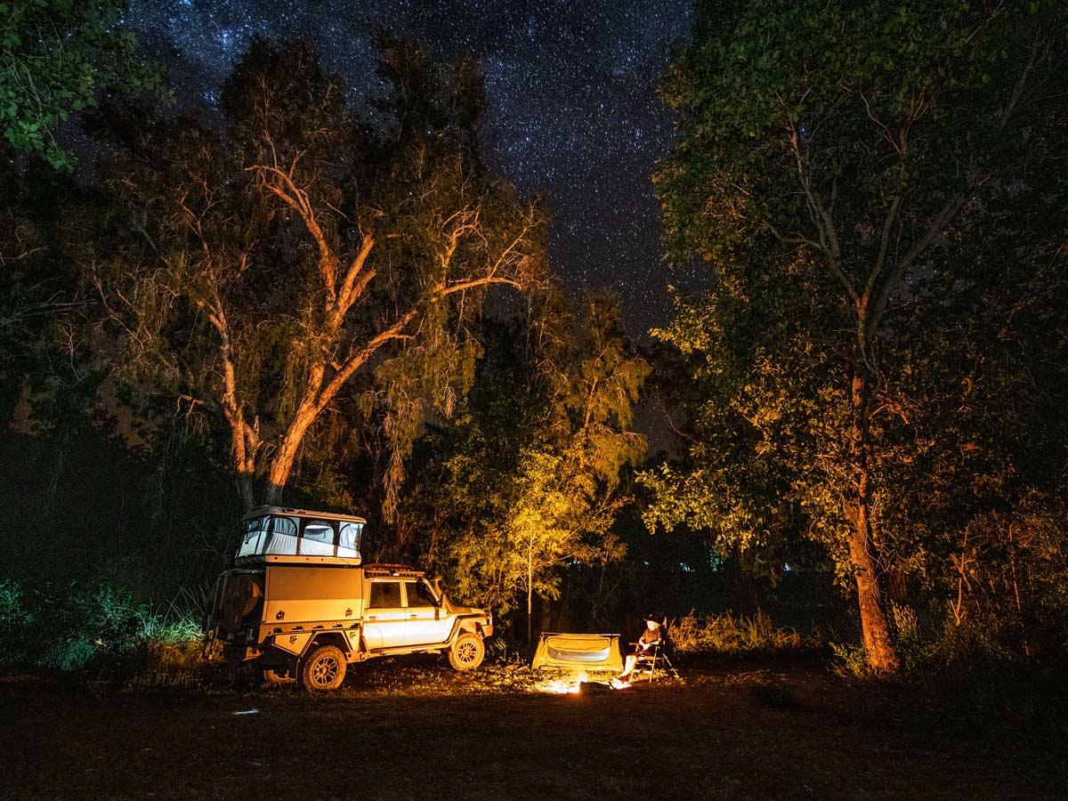 A 4WD is parked by a campfire under the stars at Lorella Springs Wildnerness on the Savannah Way, Northern Territory. (Image: Tourism NT/Sean Scott)