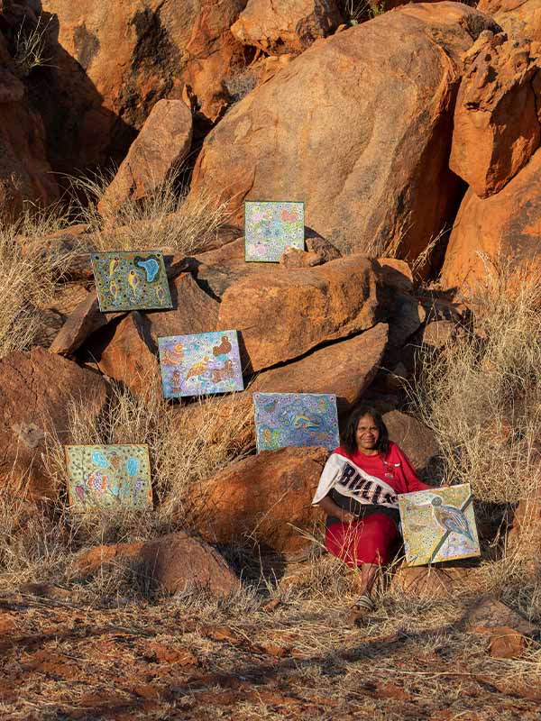 Emerging painter Sheena Dodd with her paintings Tjulpu, which means 'birds'. (Image: Meg Hansen, Mimili Maku Arts)