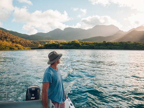 a man standing on the edge of a boat looking out at Hinchinbrook Island