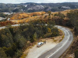 An aerial view of a car with people next to a winding road in Queenstown, Tasmania. (Image: Jason Charles Hill)